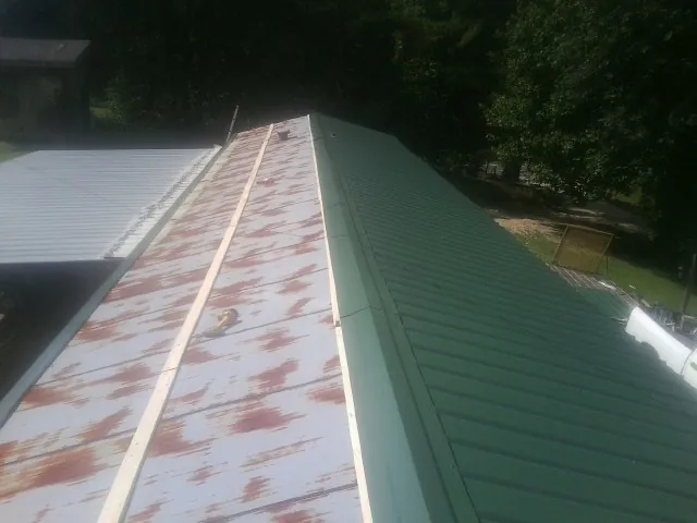 Old rusted panels beside newly installed green metal roofing — Wind Damage Roof Repair by Roofing Brothers in Pewaukee