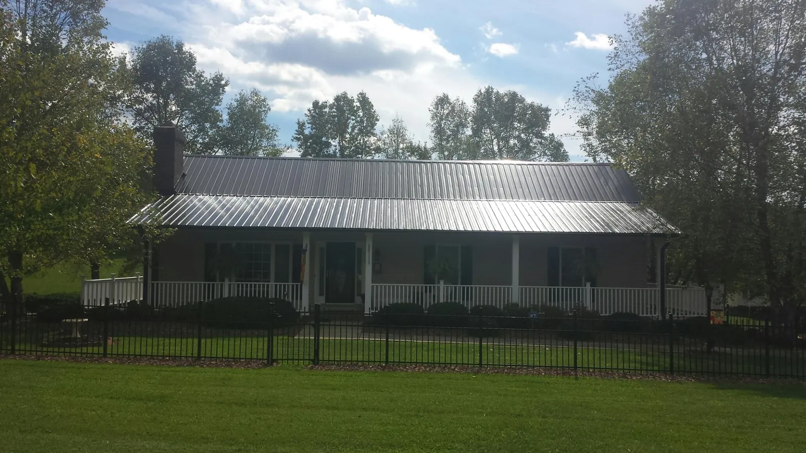 Gray metal roof on a brick ranch with a full width front porch — Gutter Guard Installation work by our crew in Pewaukee