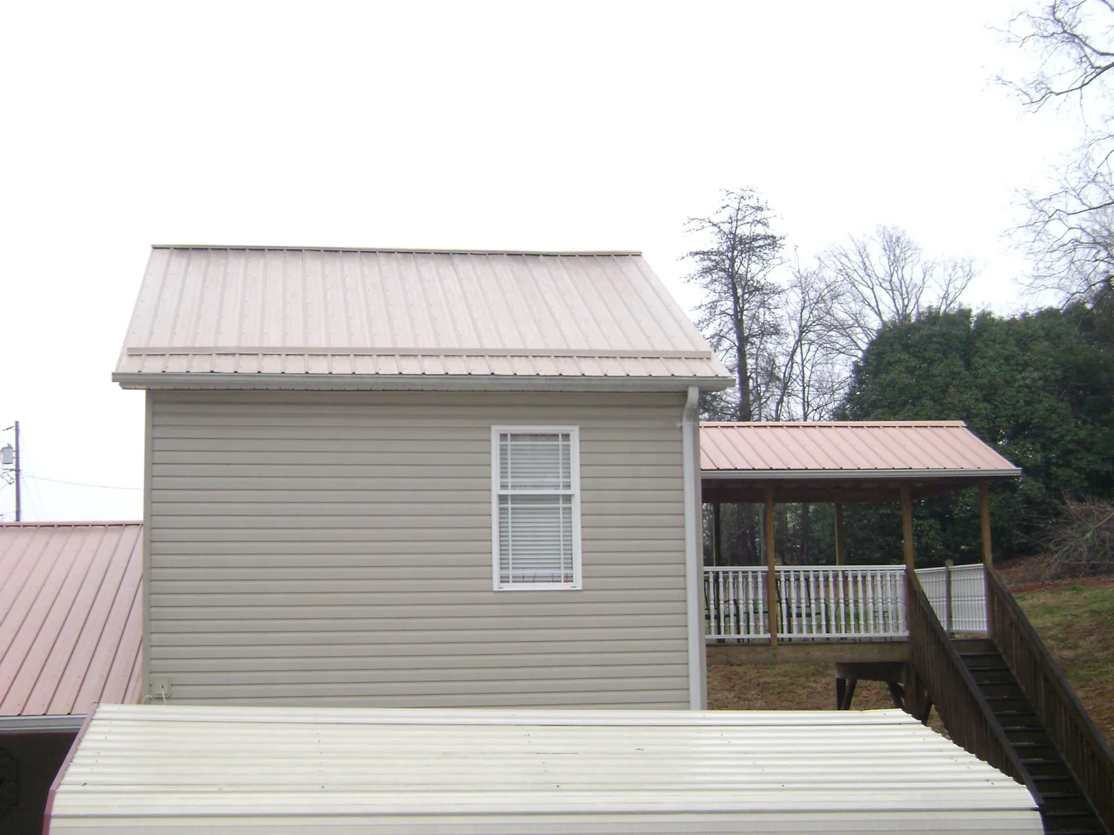 Tan metal roofs on a two story addition and attached porch, from a Roof Replacement job in Pewaukee