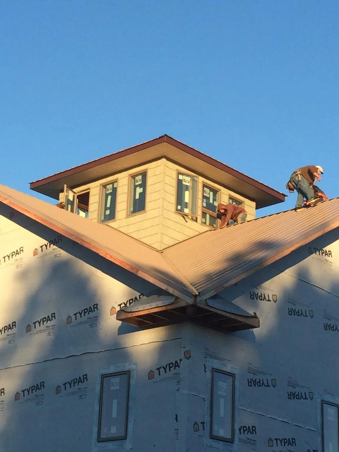 Roofers working around a rooftop cupola on a new metal roof at sunset — Roof Waterproofing in Pewaukee by Roofing Brothers